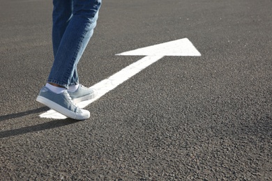 Photo of Woman going along road with arrow marking, closeup