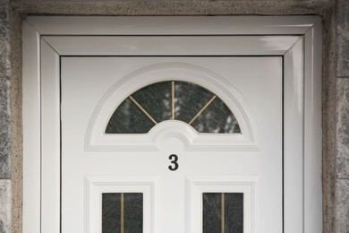 Photo of House number three on white wooden door