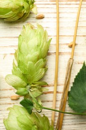 Fresh green hops and wheat seeds on white wooden table, top view