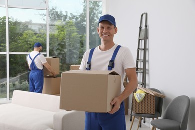 Moving service employees with cardboard boxes in room