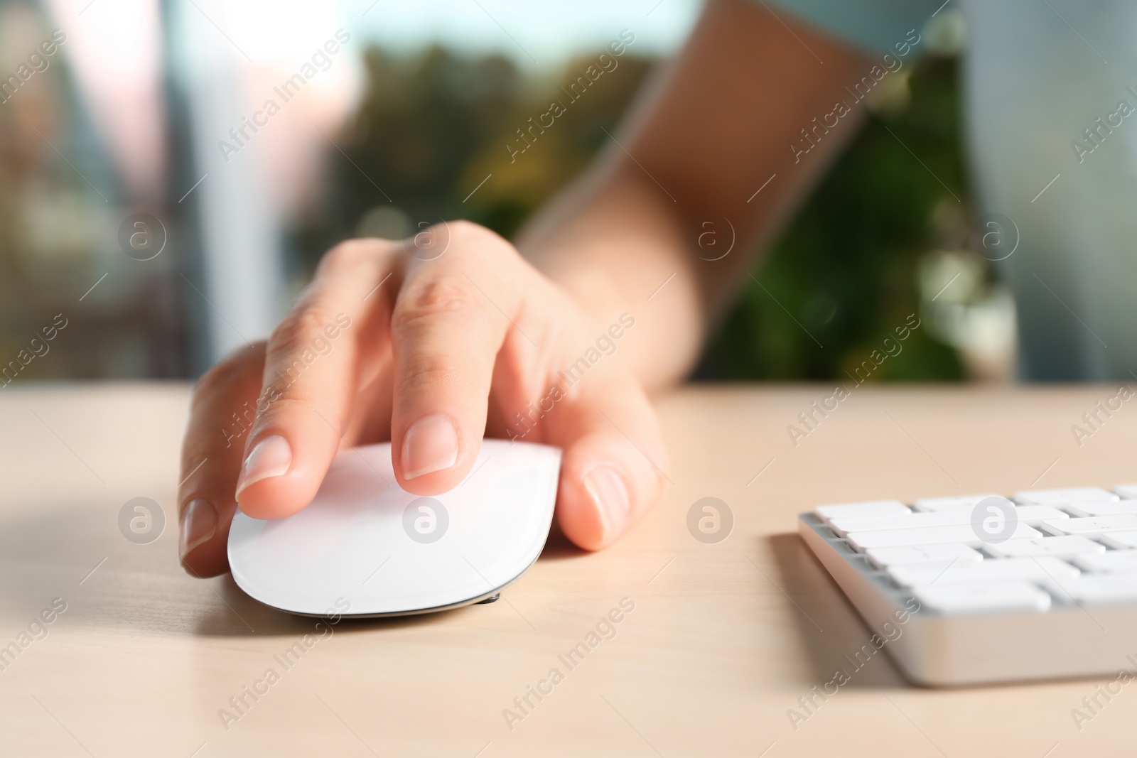 Photo of Woman using computer mouse and keyboard at table, closeup