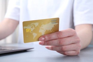 Photo of Online payment. Woman with laptop and credit card at white table, closeup