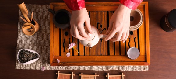 Master preparing for traditional tea ceremony at wooden table, top view. Banner design