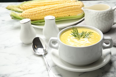 Photo of Delicious creamy corn soup served on white marble table