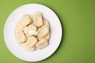 Plate of tasty lazy dumplings with butter on light green background, top view. Space for text
