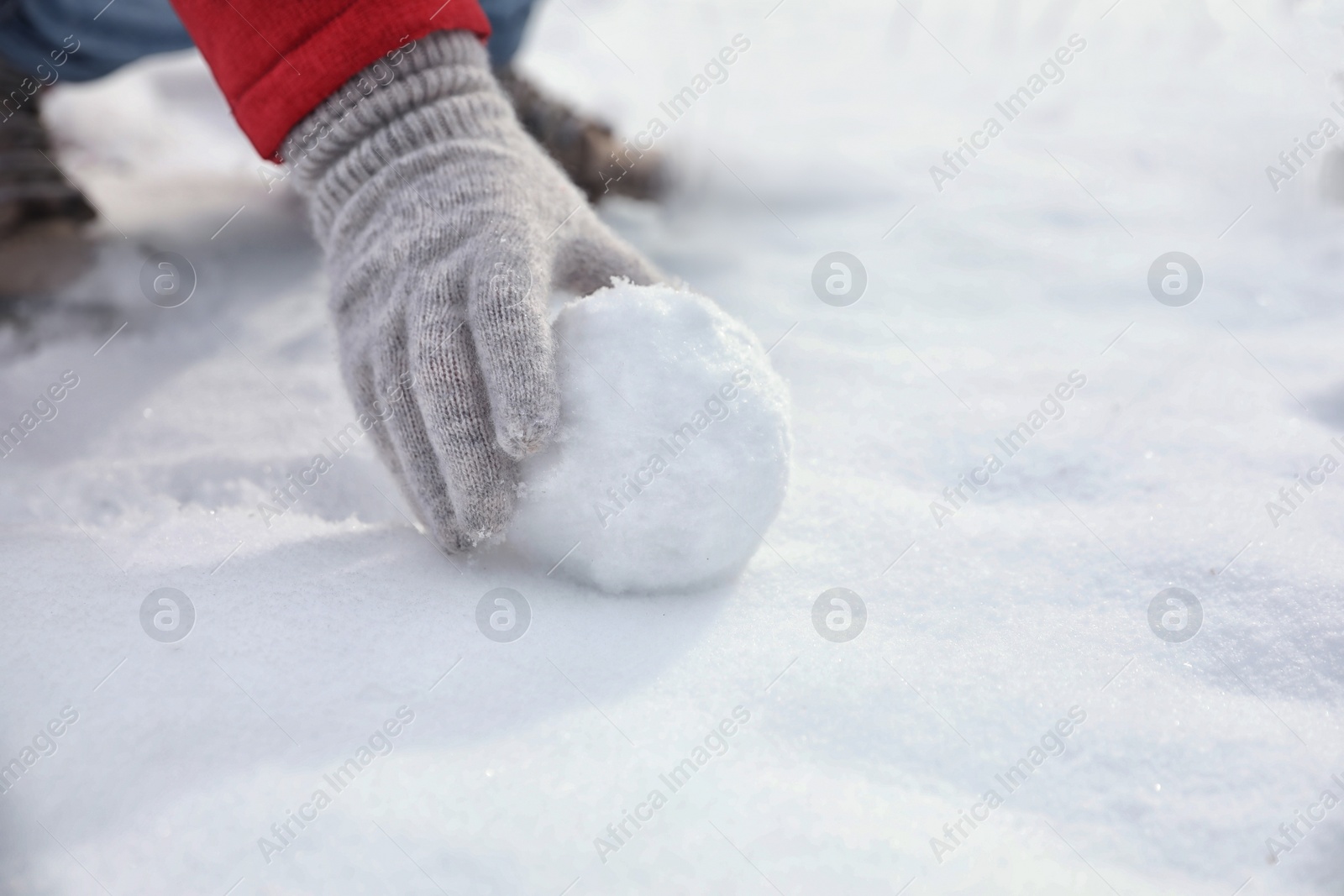 Photo of Young woman rolling snowball outdoors on winter day, closeup