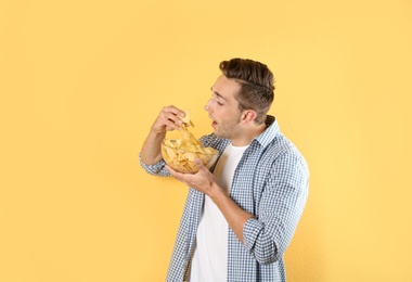 Photo of Man eating potato chips on color background