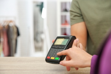 Photo of Woman using payment terminal in shop, closeup. Space for text