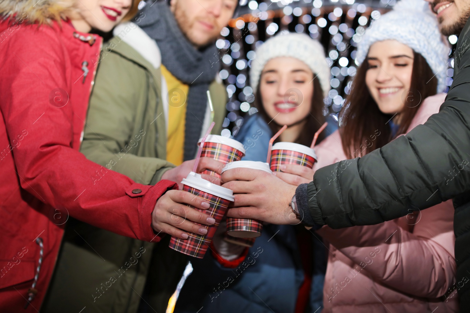 Photo of Happy friends with cups of mulled wine at winter fair