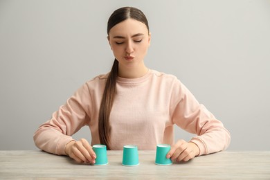 Photo of Concentrated woman playing shell game at wooden table