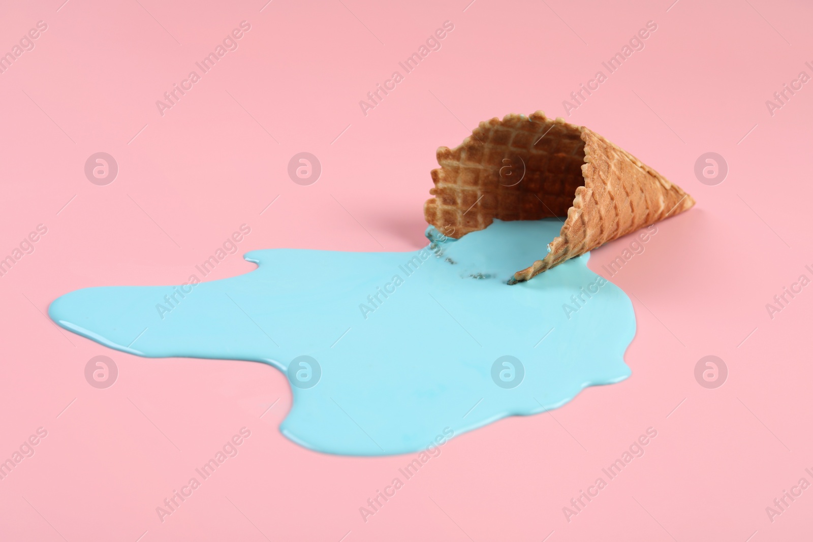 Photo of Melted ice cream and wafer cone on pink background, closeup