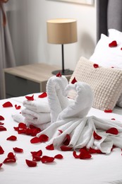 Honeymoon. Swans made with towels and beautiful rose petals on bed in room