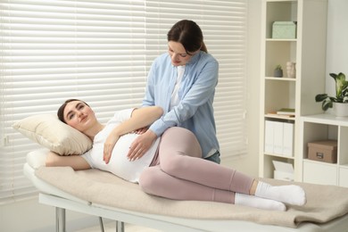 Doula taking care of pregnant woman indoors. Preparation for child birth