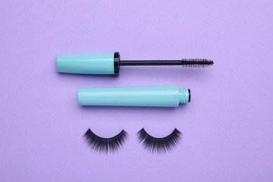 Photo of Fake eyelashes and mascara brush on lilac background, flat lay