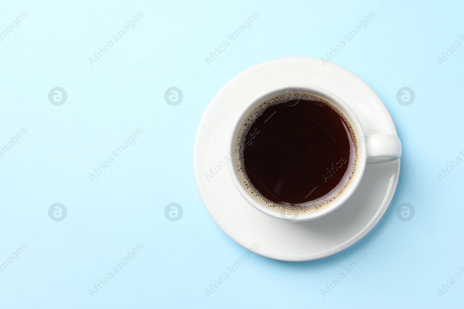 Photo of Cup of aromatic coffee on light blue background, top view. Space for text