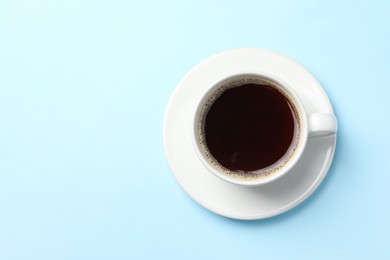 Cup of aromatic coffee on light blue background, top view. Space for text