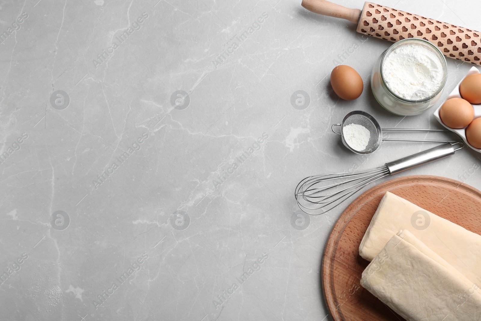 Photo of Puff pastry dough and ingredients on grey table, flat lay. Space for text