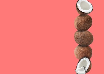 Image of Stack of fresh coconuts on salmon color background. Space for text