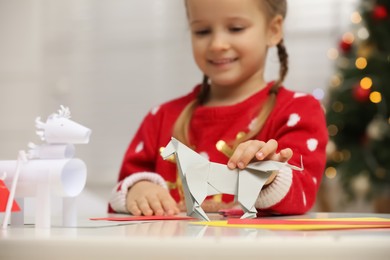 Cute little girl with paper toy for Saint Nicholas day at home, focus on hand