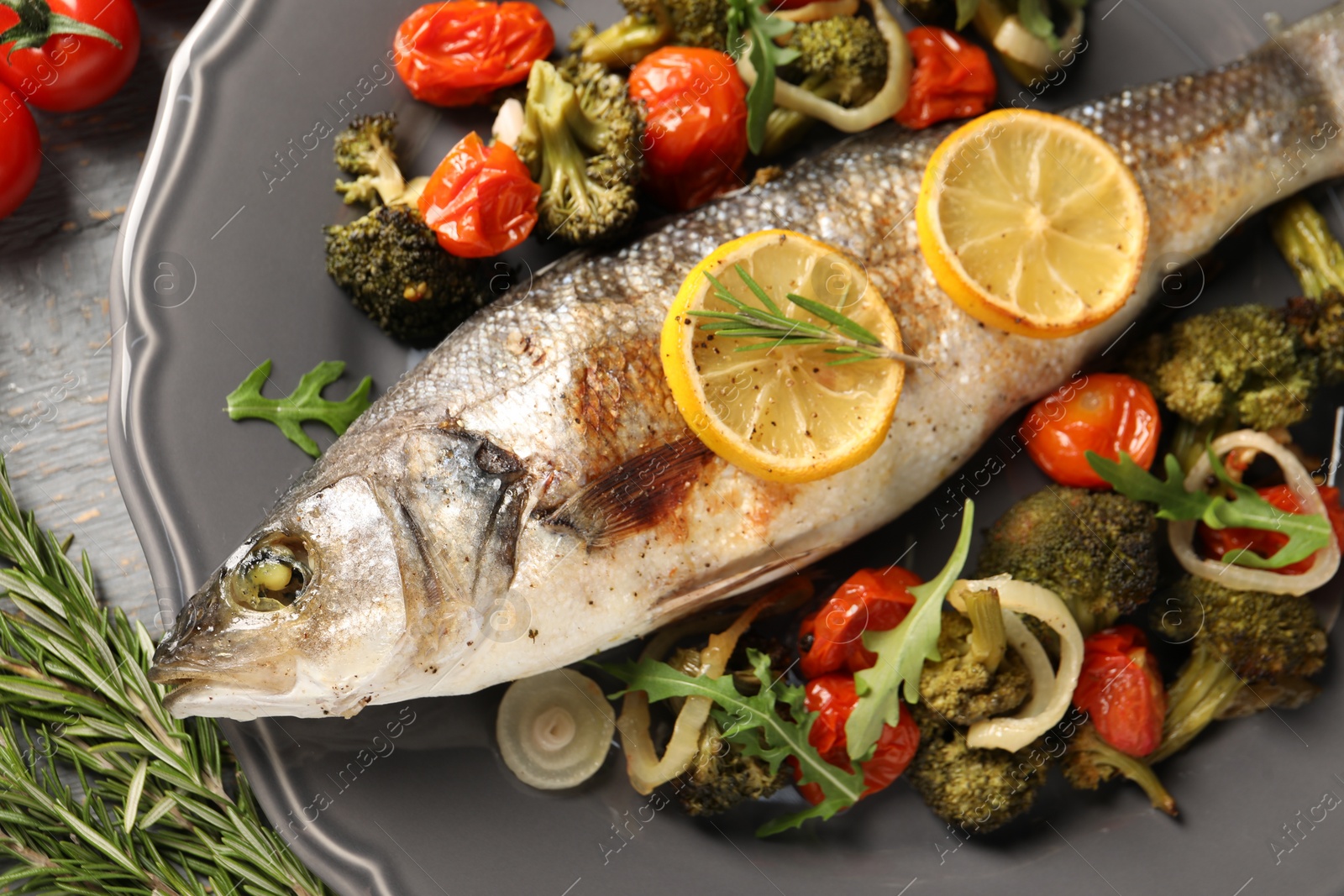 Photo of Baked fish with vegetables, rosemary and lemon on grey wooden table, flat lay