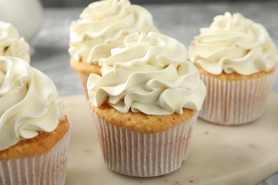 Tasty cupcakes with vanilla cream on table, closeup