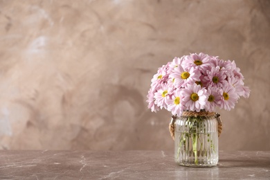 Vase with beautiful chamomile flowers on table against color background. Space for text