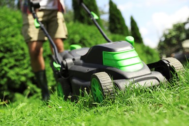 Man cutting grass with lawn mower in garden on sunny day, closeup