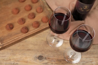 Photo of Red wine and chocolate truffles on wooden table, above view