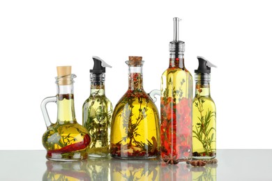 Photo of Cooking oil with different spices and herbs in bottles on light table