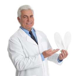 Male orthopedist showing insoles on white background