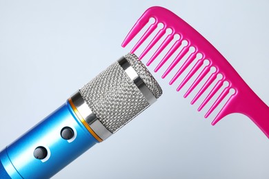 Photo of Making ASMR sounds with microphone and comb on grey background, closeup