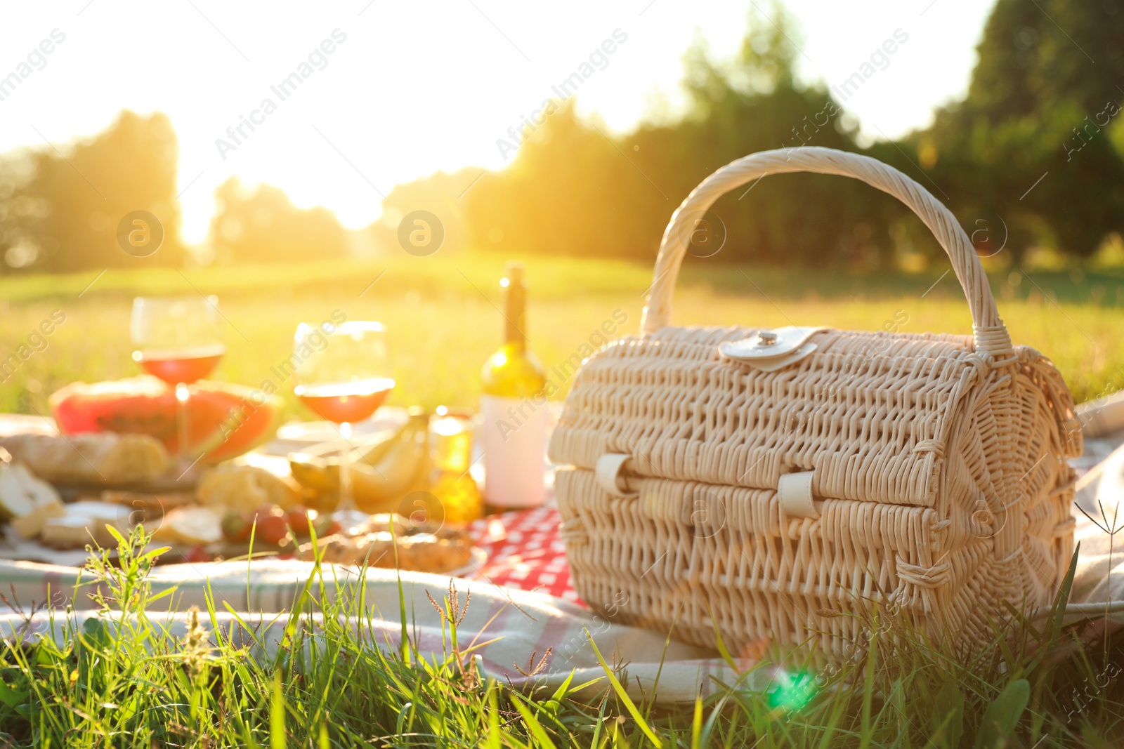 Photo of Picnic basket, food and drinks on blanket outdoors