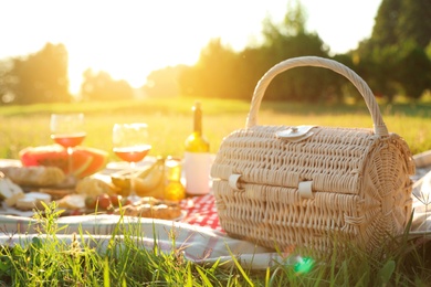 Photo of Picnic basket, food and drinks on blanket outdoors