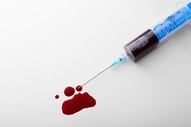 Photo of Plastic syringe with blood on white background, top view