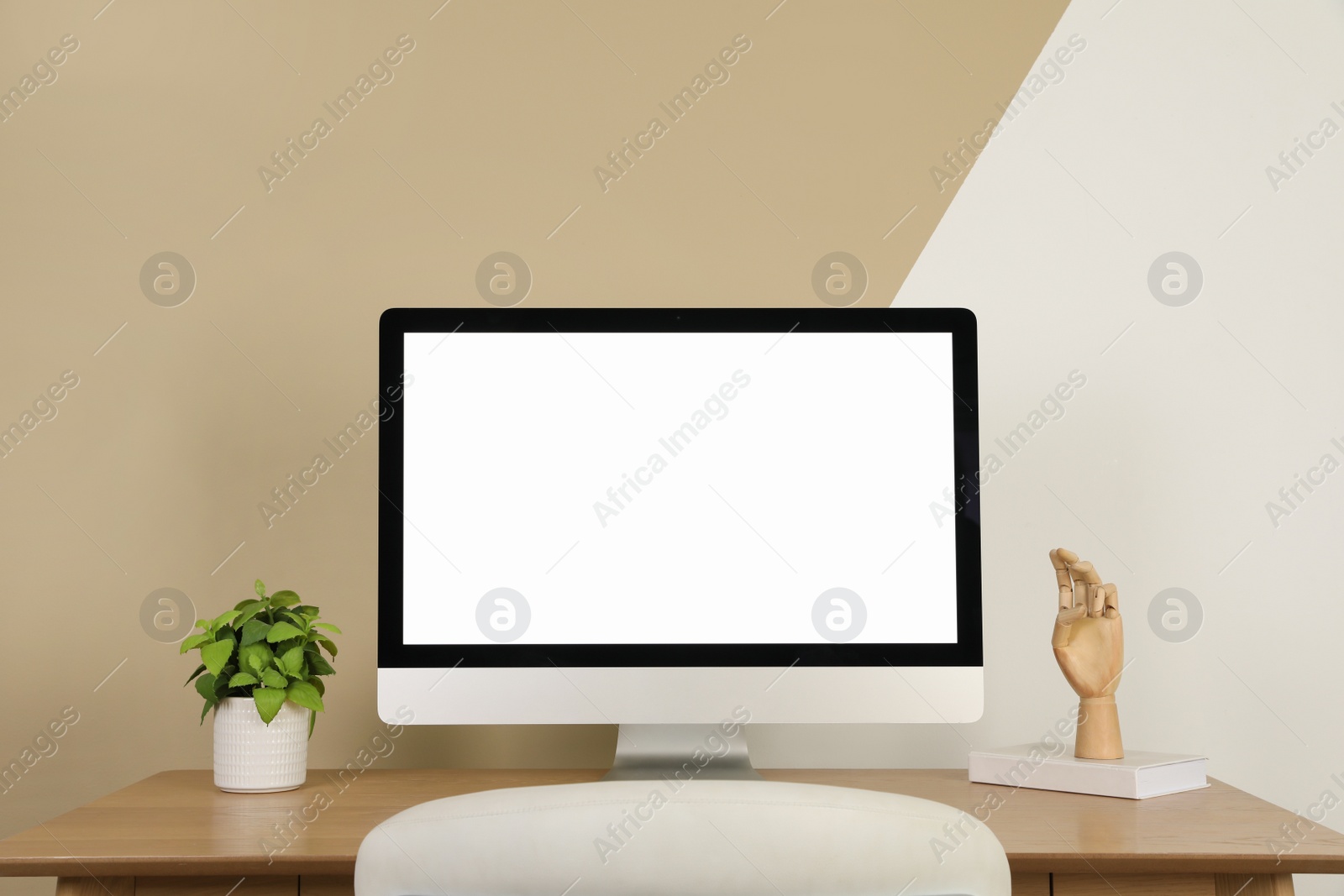 Photo of Modern computer and decor on wooden table near color wall