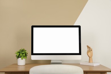 Photo of Modern computer and decor on wooden table near color wall