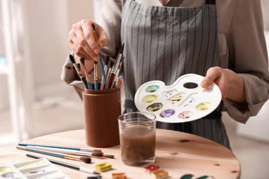 Photo of Watercolorist with palette taking brush in workshop, closeup