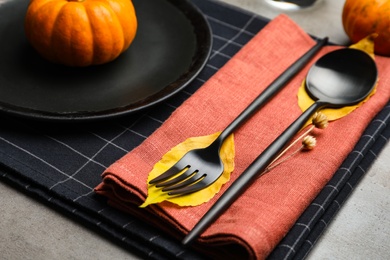 Photo of Seasonal table setting with pumpkins and autumn leaves on grey background, closeup