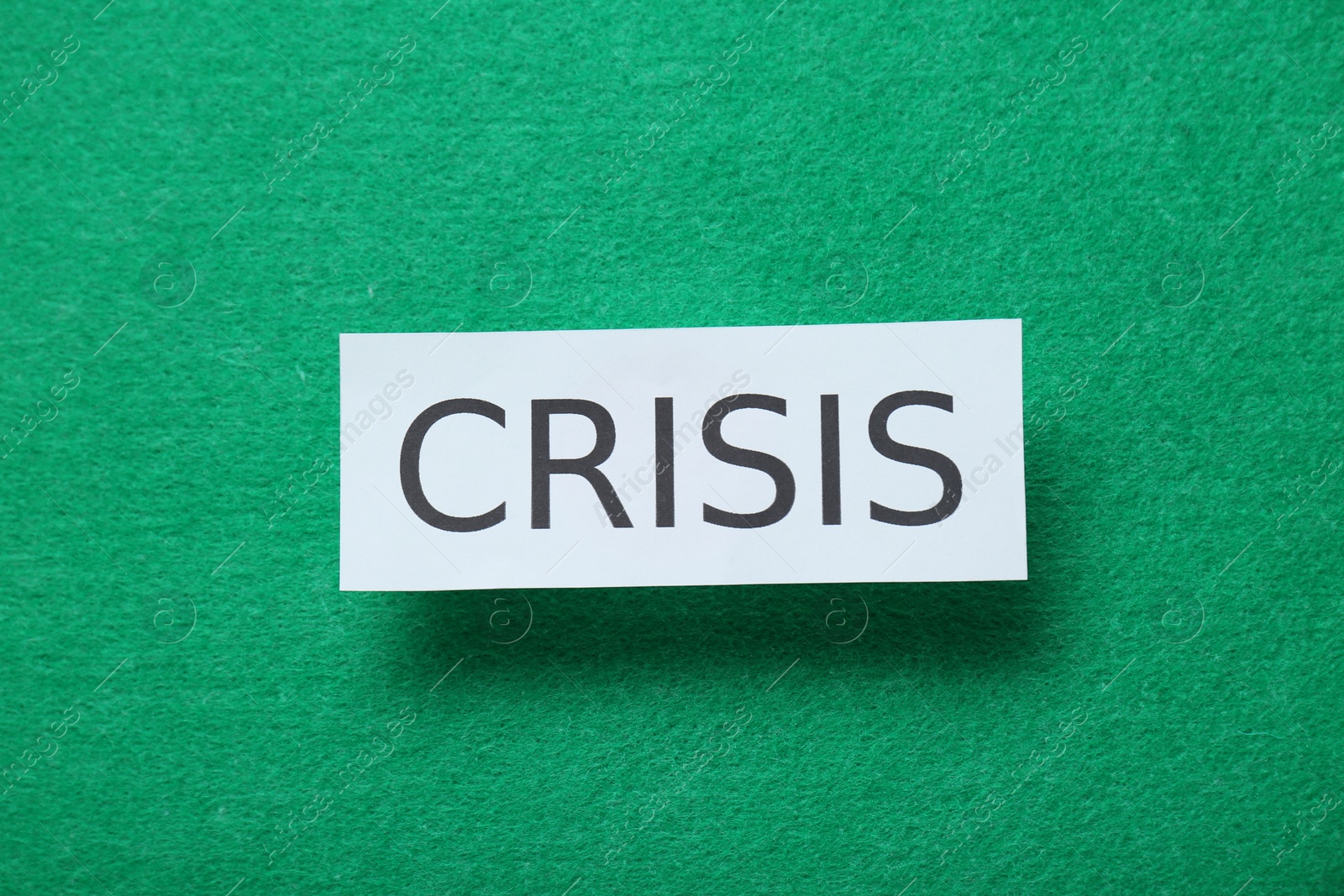 Photo of Paper sheet with word Crisis on green background, top view