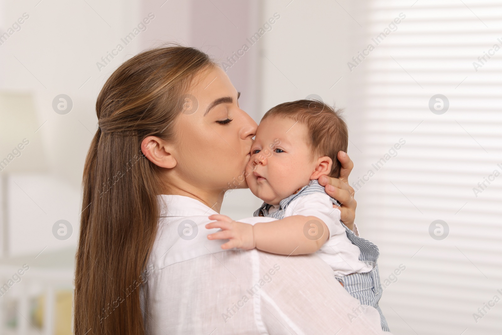 Photo of Mother kissing her cute newborn baby indoors