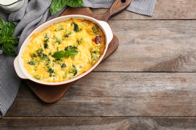 Photo of Flat lay composition with tasty broccoli casserole on wooden table. Space for text