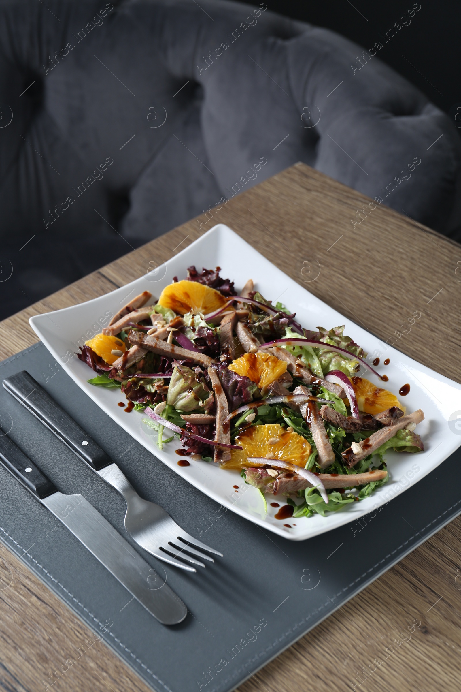 Photo of Delicious salad with beef tongue, orange and onion served on wooden table