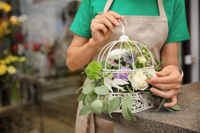 Photo of Female florist making beautiful composition in flower shop, closeup
