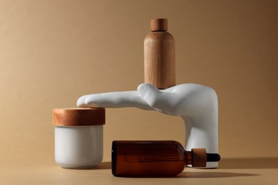 Photo of Bottles and jar of cosmetic products on dark beige background