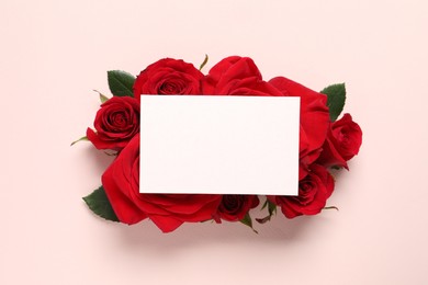 Blank card and beautiful red roses on pale pink background, top view. Space for text