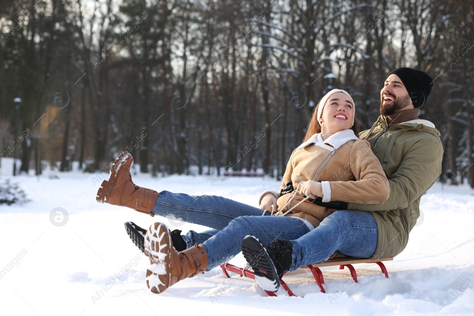 Photo of Happy young couple sledding outdoors on winter day