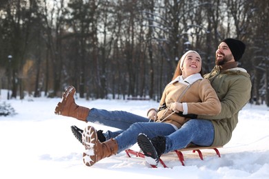 Photo of Happy young couple sledding outdoors on winter day