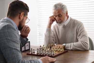 Men playing chess during tournament at table indoors