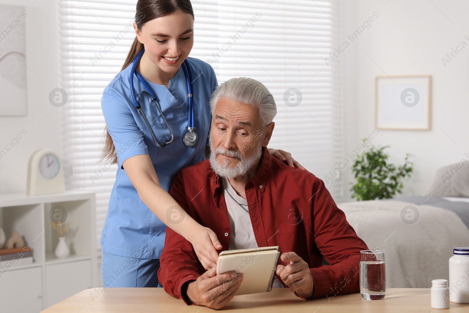 Photo of Young healthcare worker consulting senior man at wooden table indoors