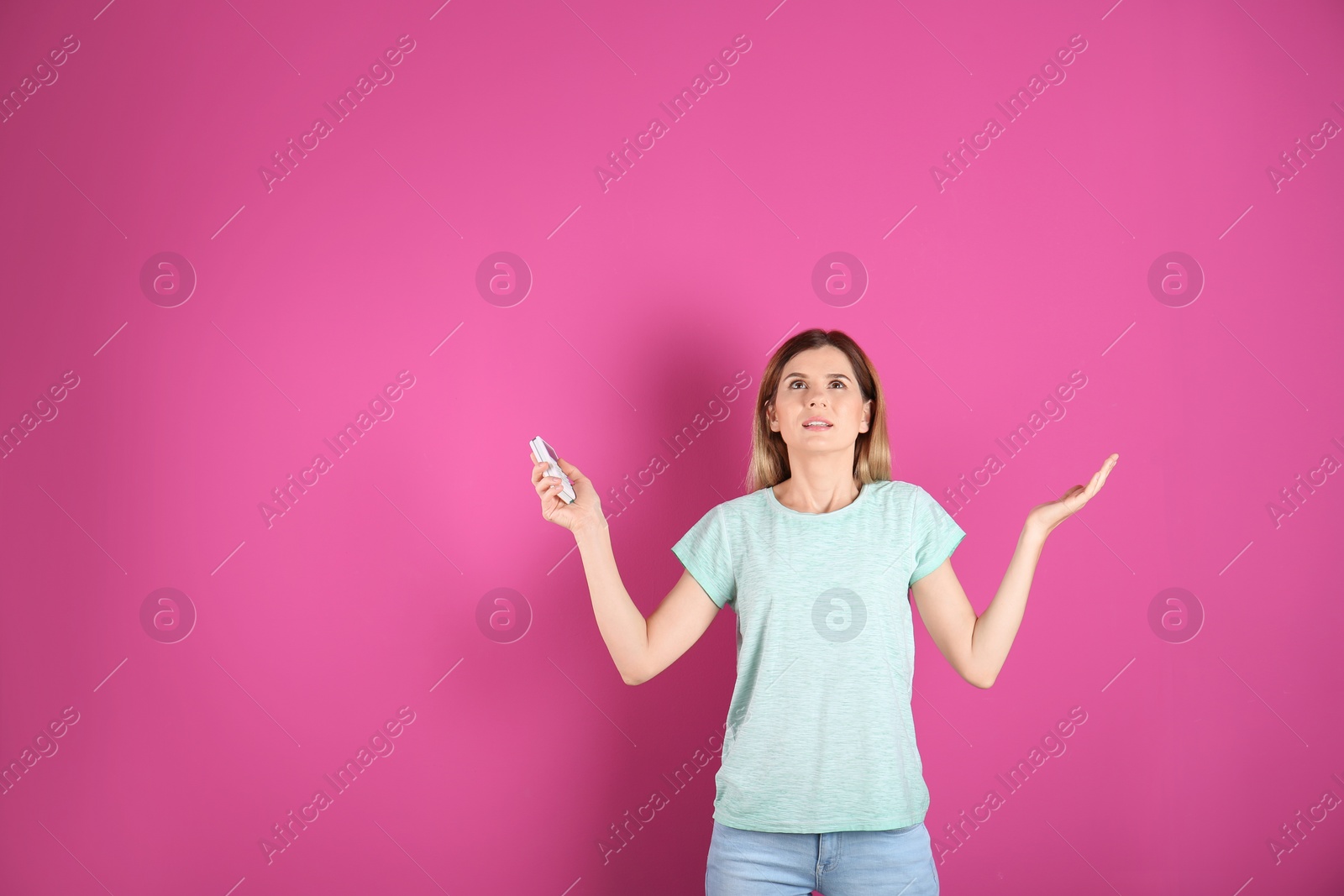 Photo of Woman with air conditioner remote on color background